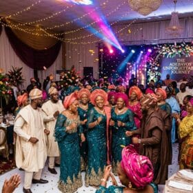 Nigerian wedding reception with guests in colourful outfits dancing and celebrating at an owambe